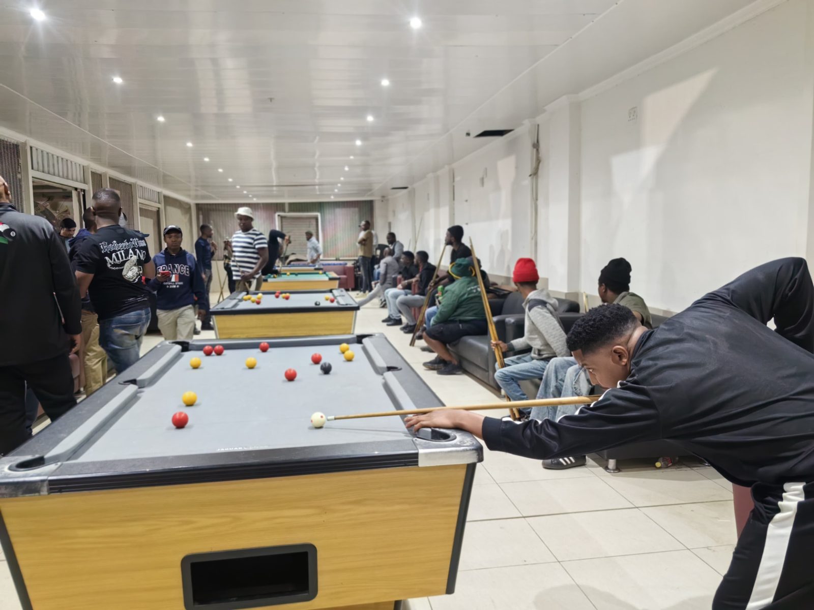 Players lining up shots on league night with spectators around the tables