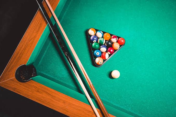 Racked balls and two cues on a green table